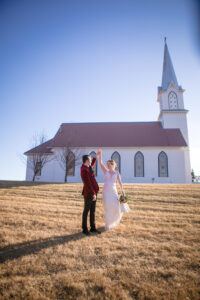 groom spins bride in front of small country church